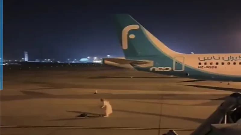شخص يصلي في مدرج الطائرات وموظفة تقاطعه .. فيديو